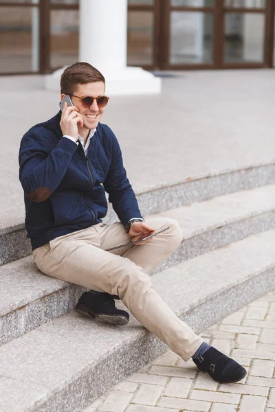 Business man speaks by mobile phone sitting on the stairs