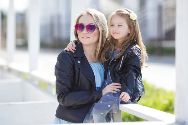 Fashionably dressed mother and daughter on the street in the spring