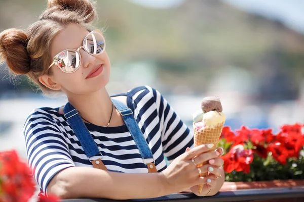Pregnant woman with ice cream cone near the ocean