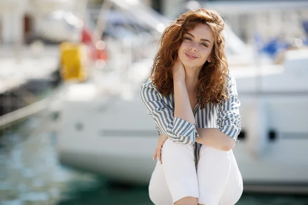 Beautiful girl on the pier next to the yacht club
