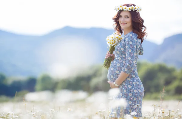 Pregnant woman in field with bunch of daisies