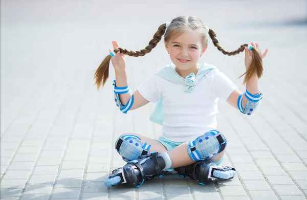 Little girl on roller skates in park.