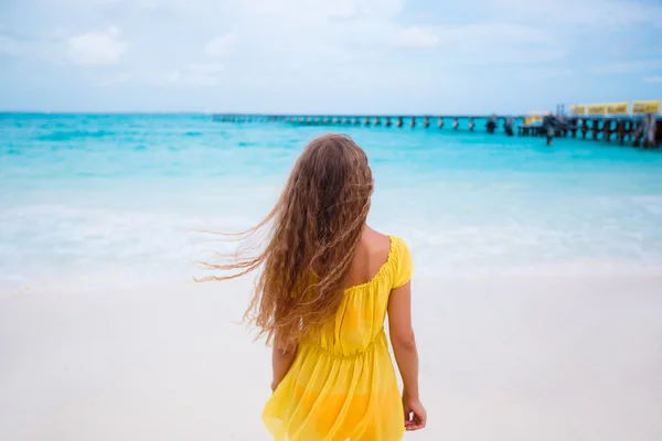 A woman in a yellow sundress on a tropical beach