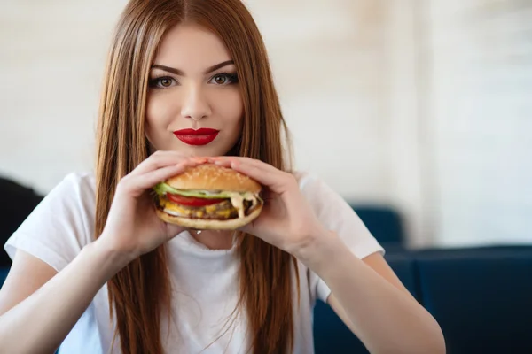 Lady with a hamburger for a table in a cafe