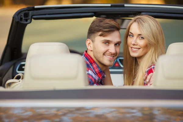 Loving couple in a black convertible in the autumn park.