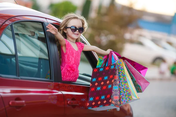 Happy child in the car with colored bags