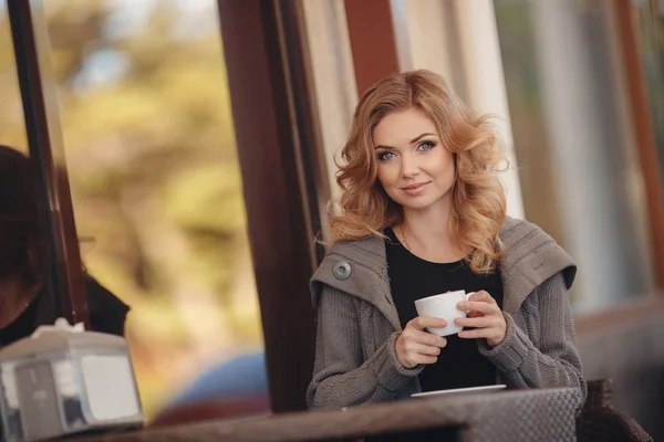 Woman drinking coffee at a table in a cafe