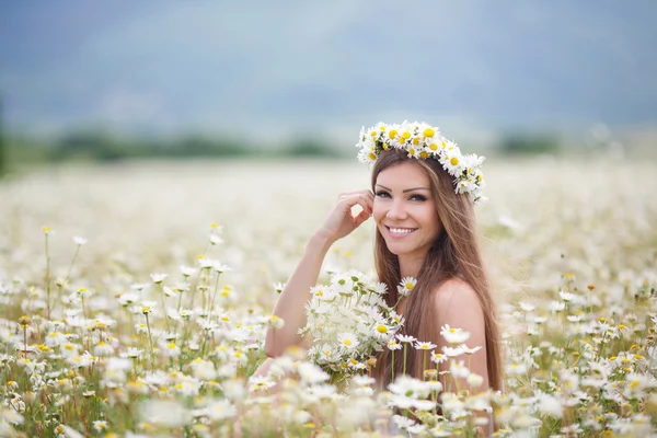 Beautiful young woman in a field of blooming daisies