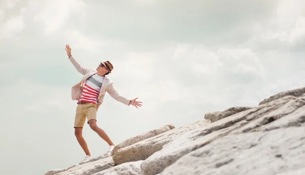 Young  man dancing on rock, feel freedom, blue sky background.