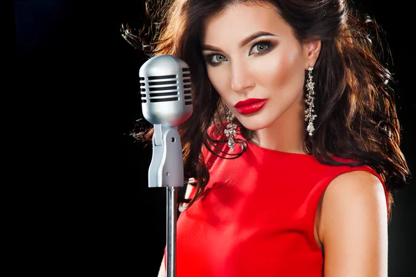 Beautiful Singing Girl. Beauty Woman in red dress with Microphone