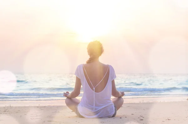 Woman practicing yoga at sunrise beach