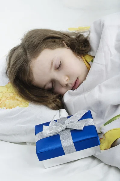 Little girl sleeping in bed with gift