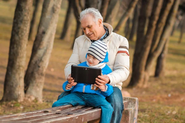 Grandfather and grandson with tablet outdoors