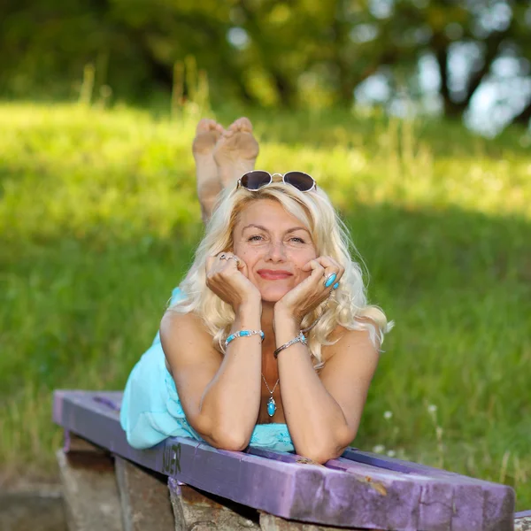 Mature blonde in vintage dress on bench