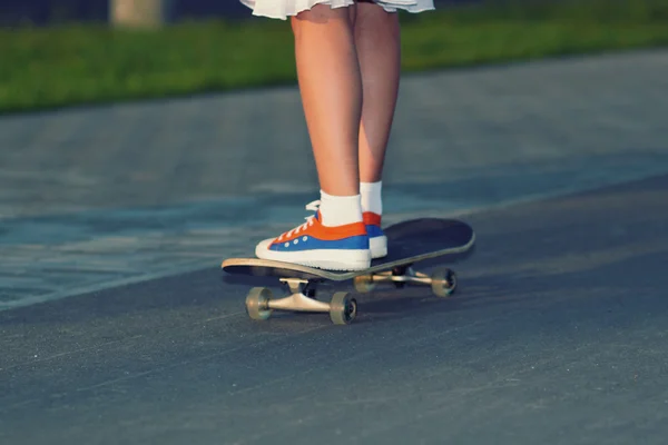 Teenager legs in sneakers on skateboard