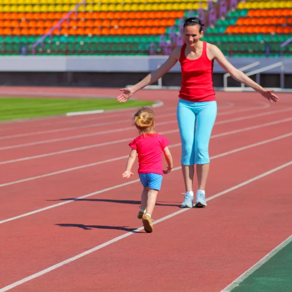 Mother and daughter exercising at stadium