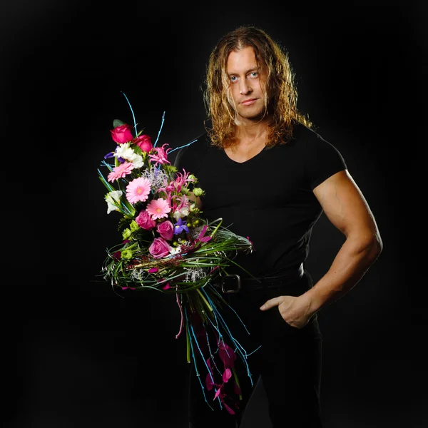 Muscular man holds a bouquet of flowers