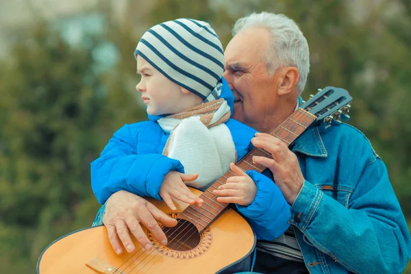 Grandfather and grandson playing guitar