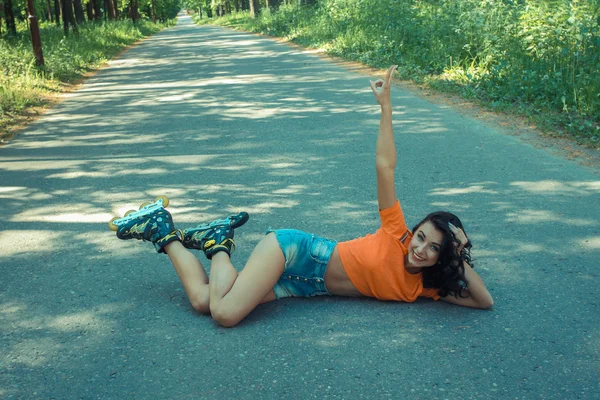 Woman in roller skates, sitting on the road