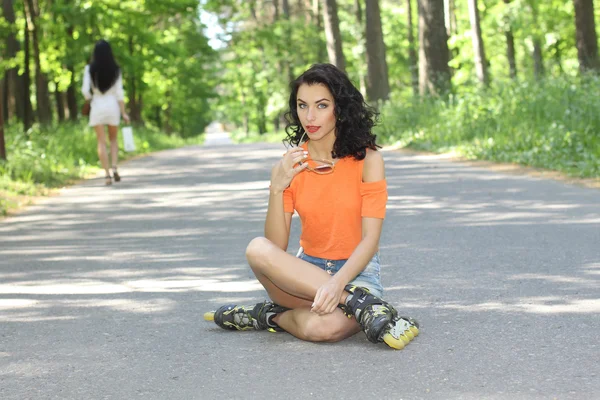 Woman in roller skates, sitting on the road