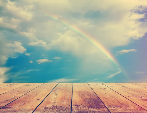 Rainbow, sunset sky and wooden floor