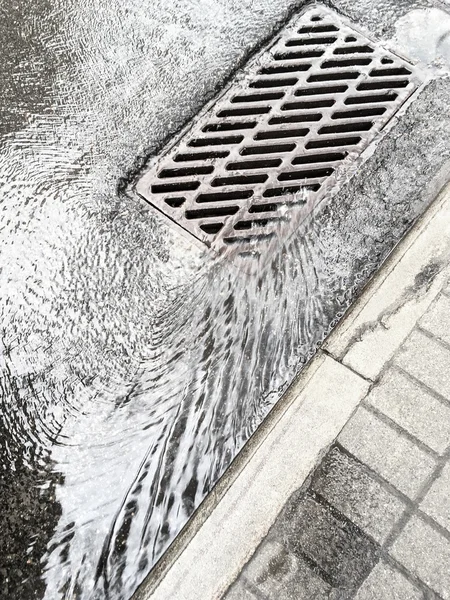 Water from heavy rain flows into a sewer drain