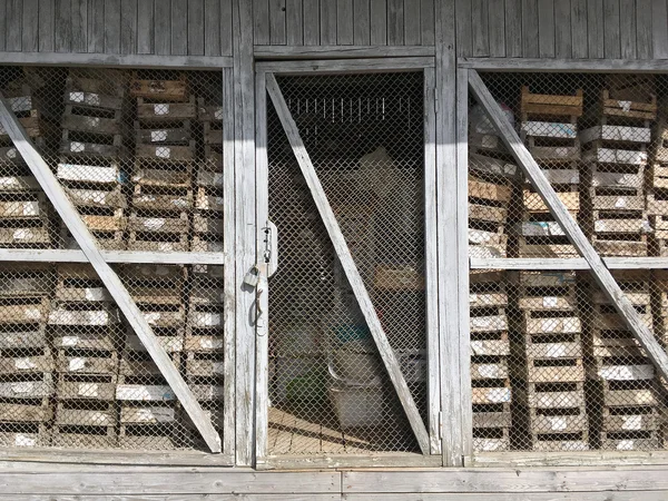 Old wooden barn with closed door and empty wooden crates