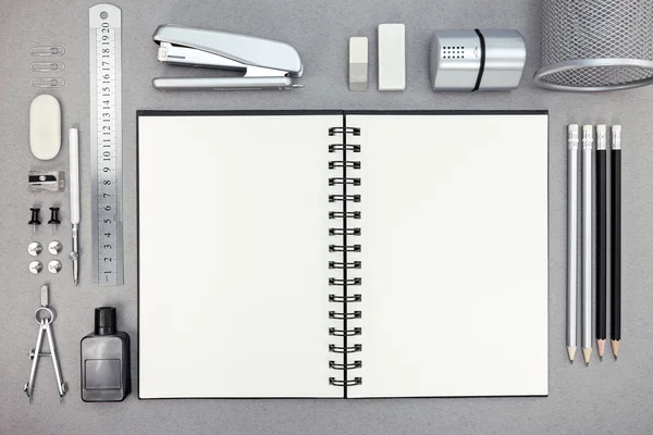 Top view of gray workplace with blank notebook and drawing tools