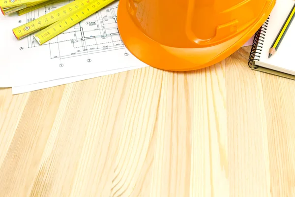 Orange safety helmet with ruler and blueprints