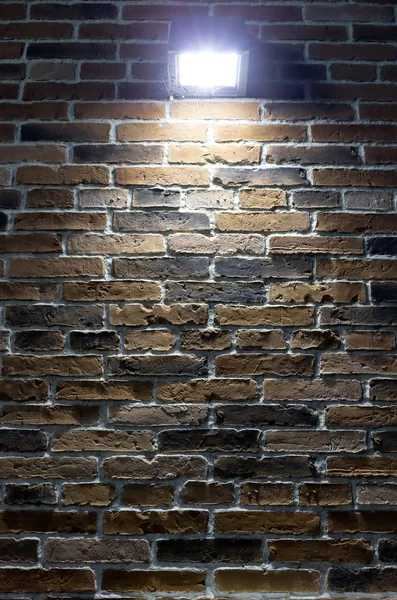 Spotlight with web on brick wall at night