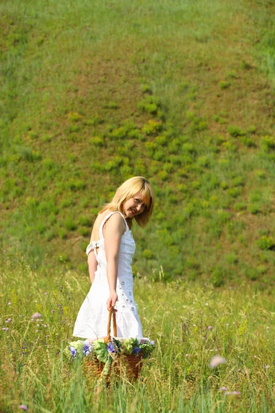 Sexy girl walk away with basket on a meadow