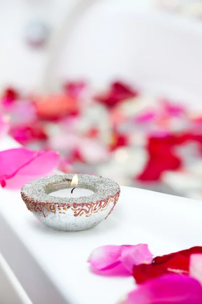 Spa treatment bathtub with floating rose petals and candles