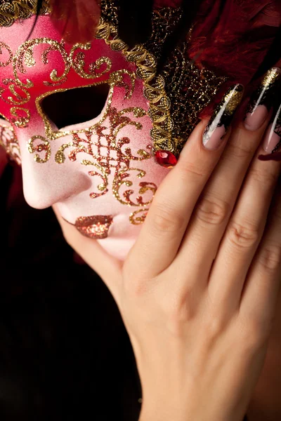 Human hand with beautiful manicure holding venetian mask
