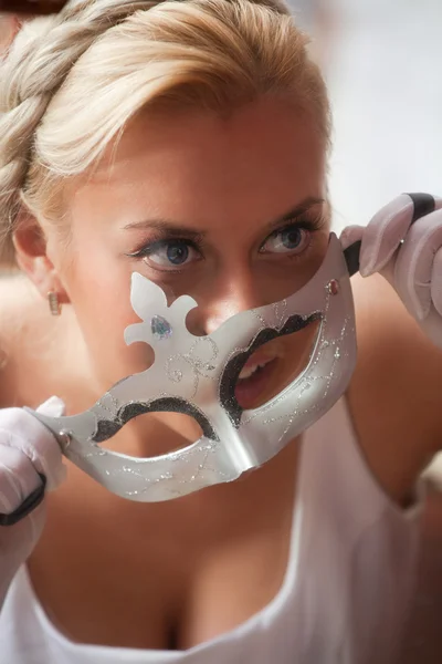 Beautiful young woman applying venetian carnival mask