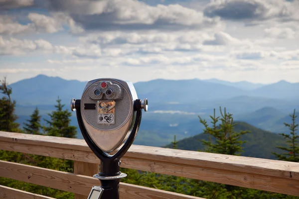 Public view binoculars, operated with coins, on a deck, with the Adirondack mountians in the background