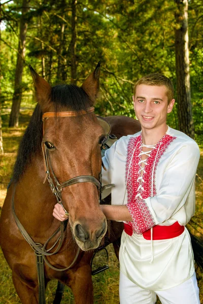 Young Ukrainian with a horse in the forest