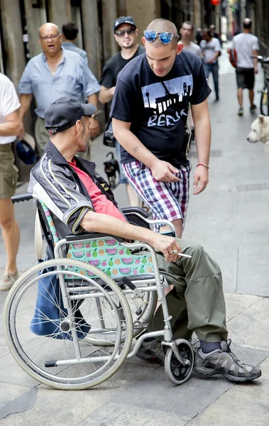 Man in a wheelchair asks for help to passers in the Gothic Quarter