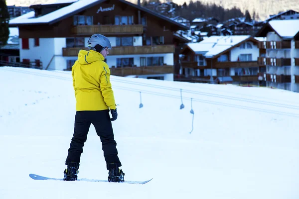 Young man with ski suit practicing snowboarding