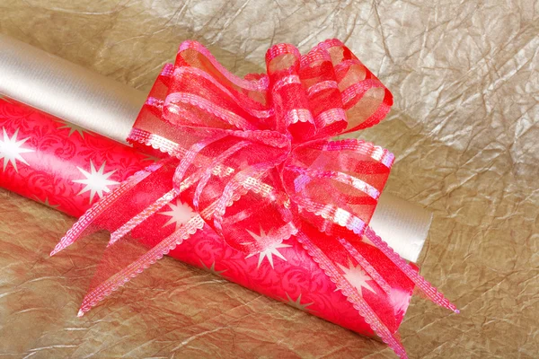 Rolls of multicolored wrapping paper with red bow for gifts on g