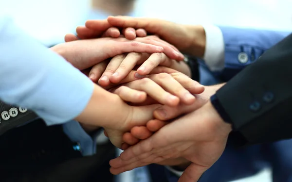 Close-up of business partners making pile of hands at meeting