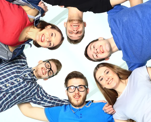 Portrait of confident college students forming huddle over white background