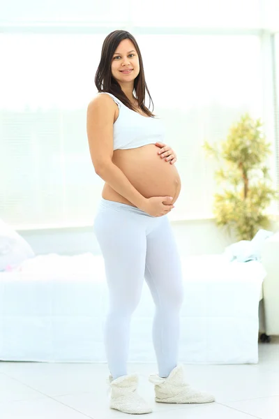 Pregnant woman stands and stroking her baby bump
