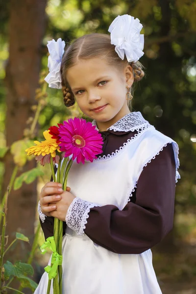 Portrait of a beautiful young first-grader in a festive school u