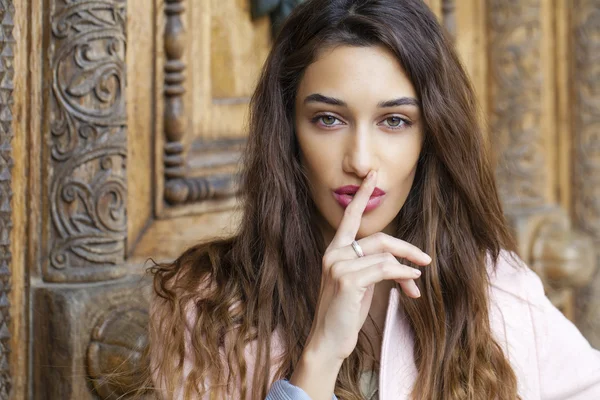 Portrait of attractive young woman with finger on lips