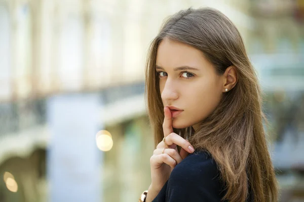 Portrait of attractive young haired woman with finger on lips