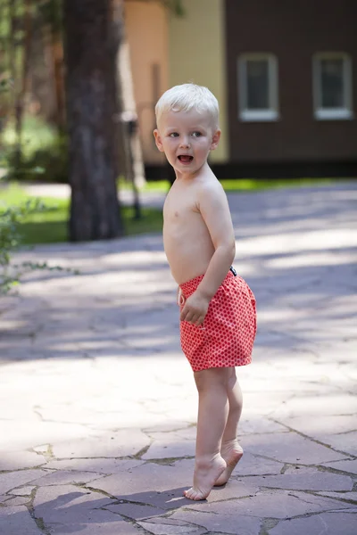 Portrait of blonde baby boy in red shorts