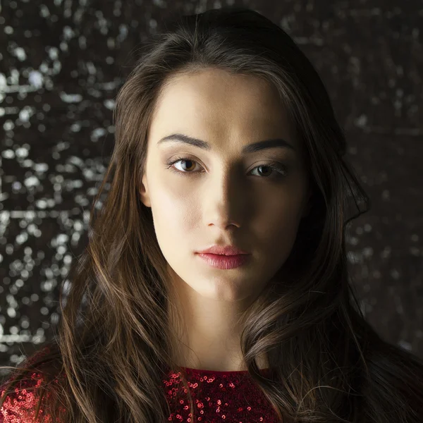 Young brunette woman on dark studio wall background