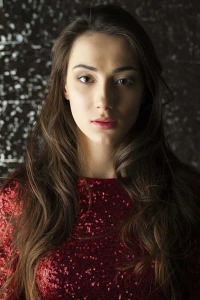 Young brunette woman on dark studio wall background