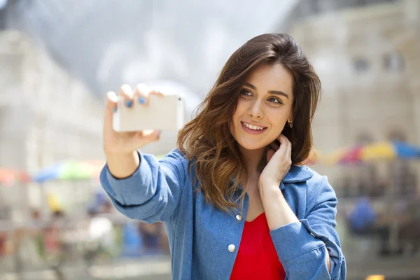 Beautiful, smiling woman take a picture of herself with a smartp