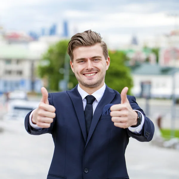 Businessman showing ok sign in front of an office building
